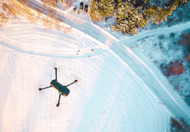black quadcopter drone flying over snow field during daytime